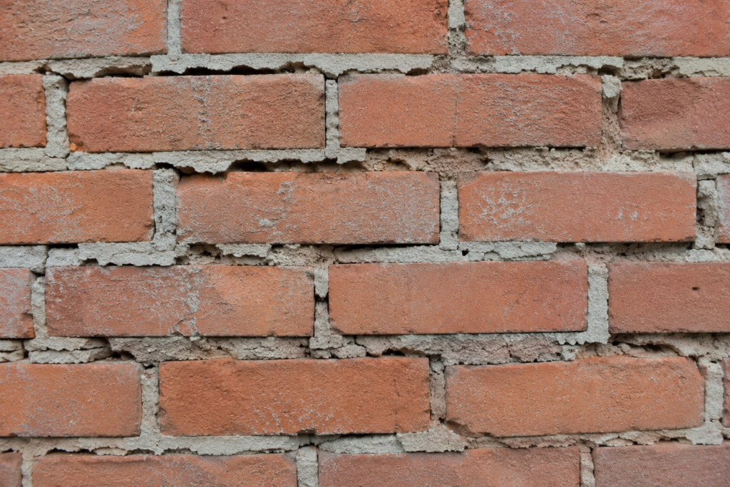 Common Mortar Failure Problems A brick wall with crumbling mortar indicating poor adhesion